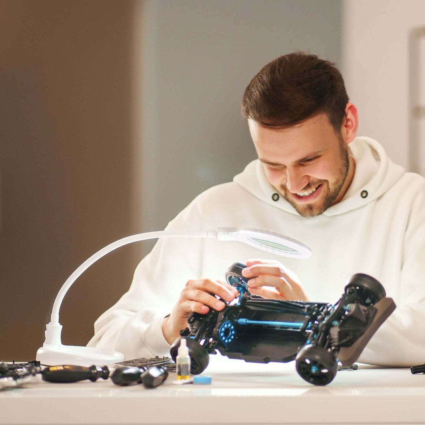Man using Lumeno 680X LED magnifying lamp while assembling a model car, showcasing bright LED lighting for detail work.